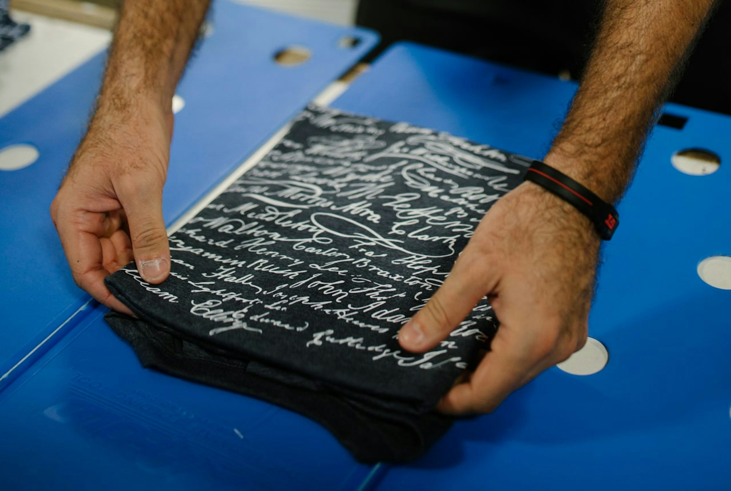 A man folds shirts using a folding apparatus 